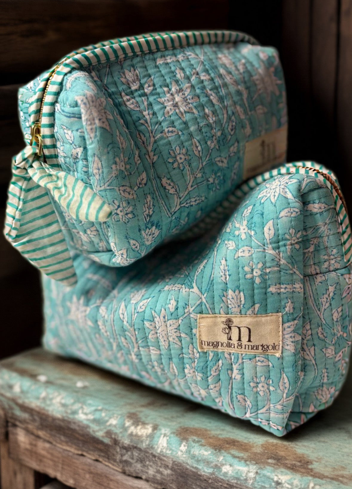 Turquoise quilted bag with floral pattern on a wooden surface
